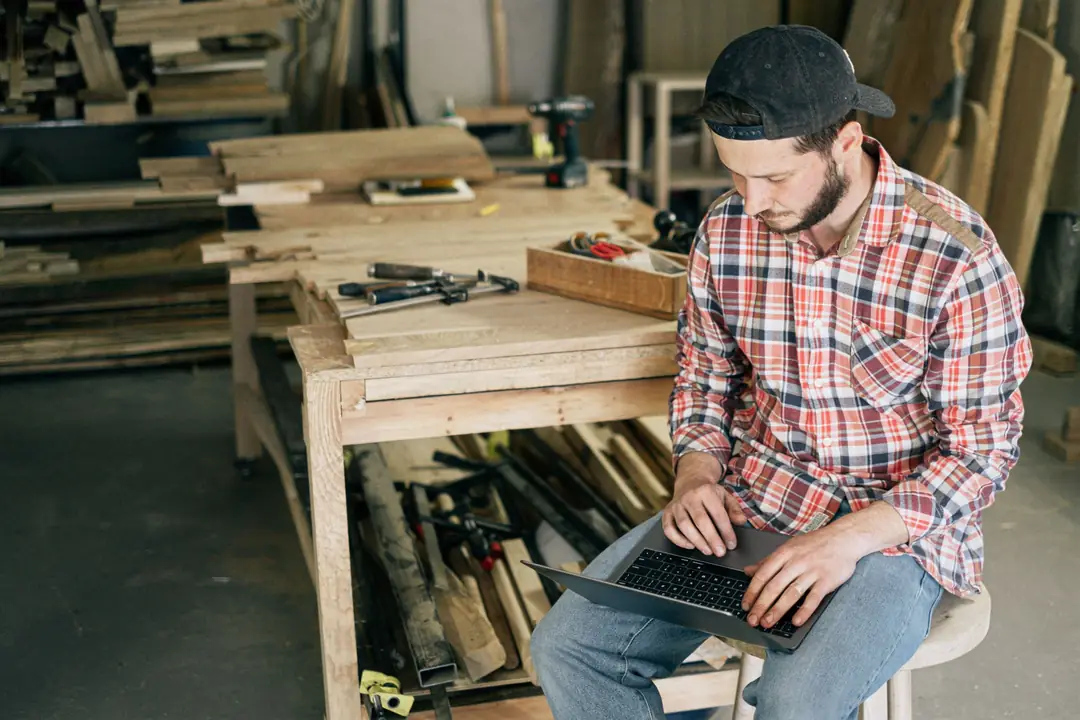 Carpenter working on a laptop in his workshop