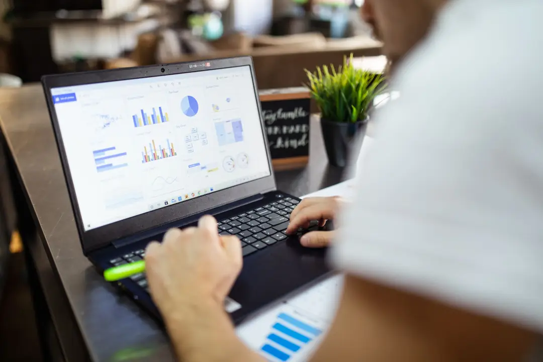 Comptable travaillant sur son ordinateur portable, entouré de tableaux et d'analyses