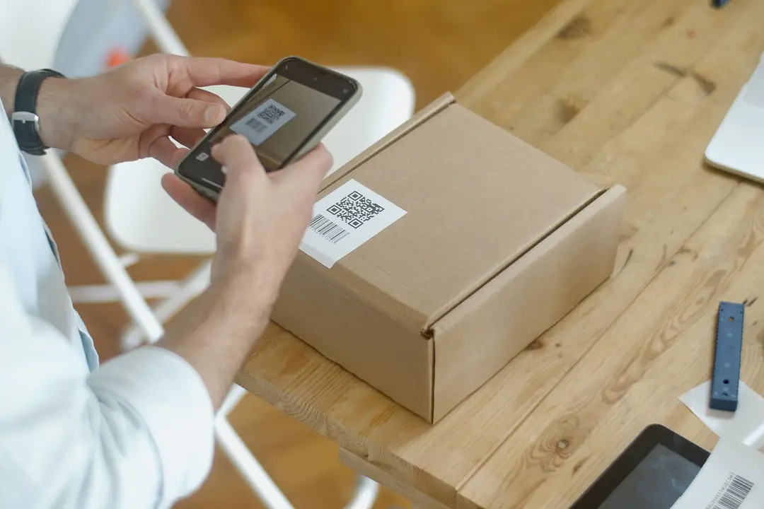 Mână care scanează cu smartphone-ul un cod QR de pe hârtie