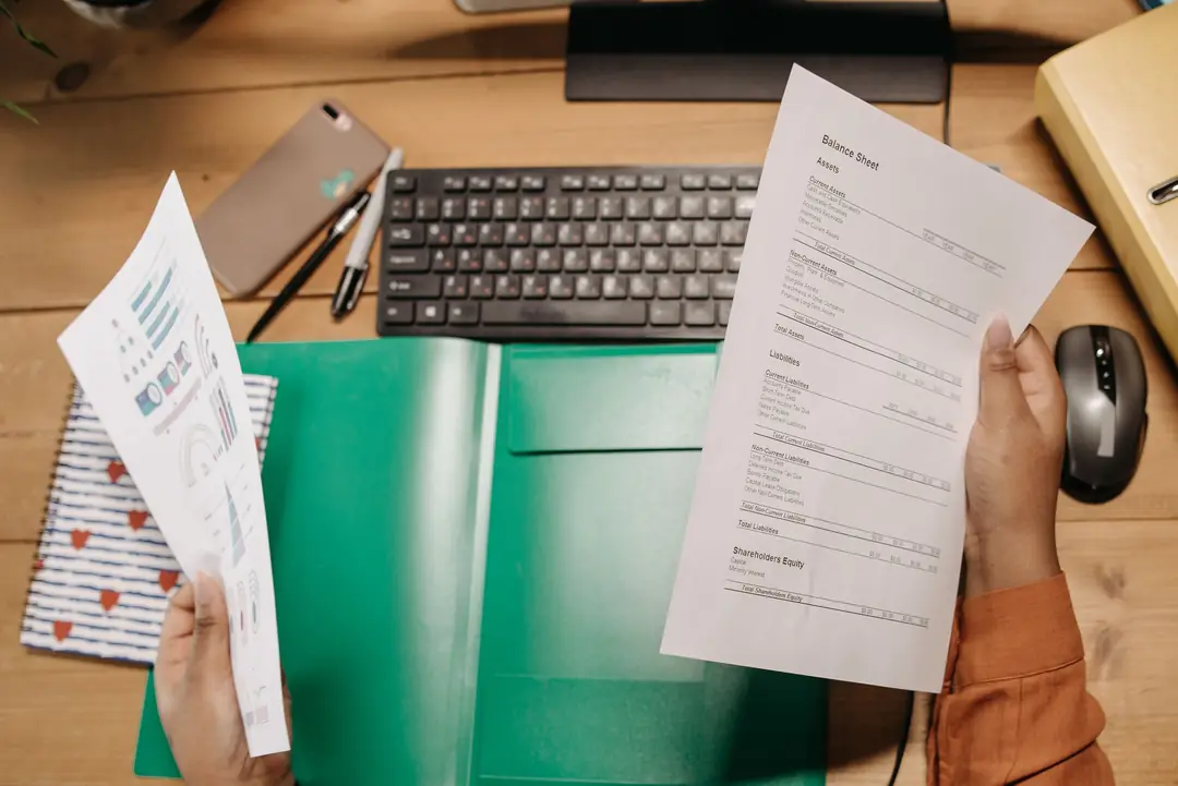 Hands holding bank statements over a desk