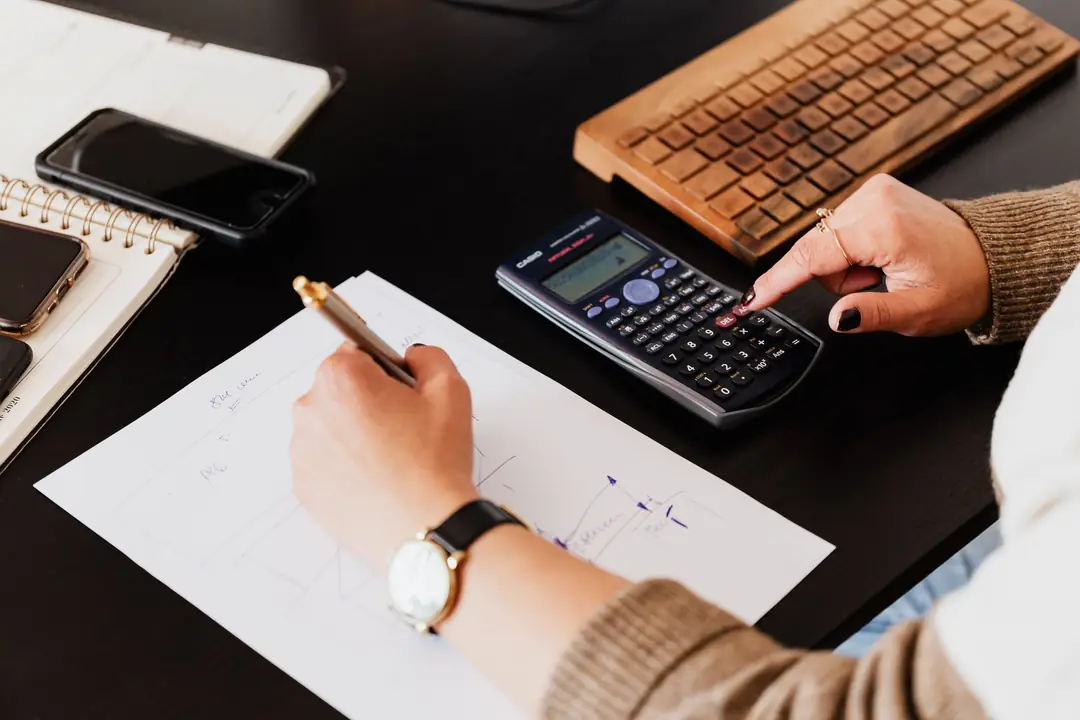 Contabilă care notează cifre și calculează cu calculatorul de buzunar